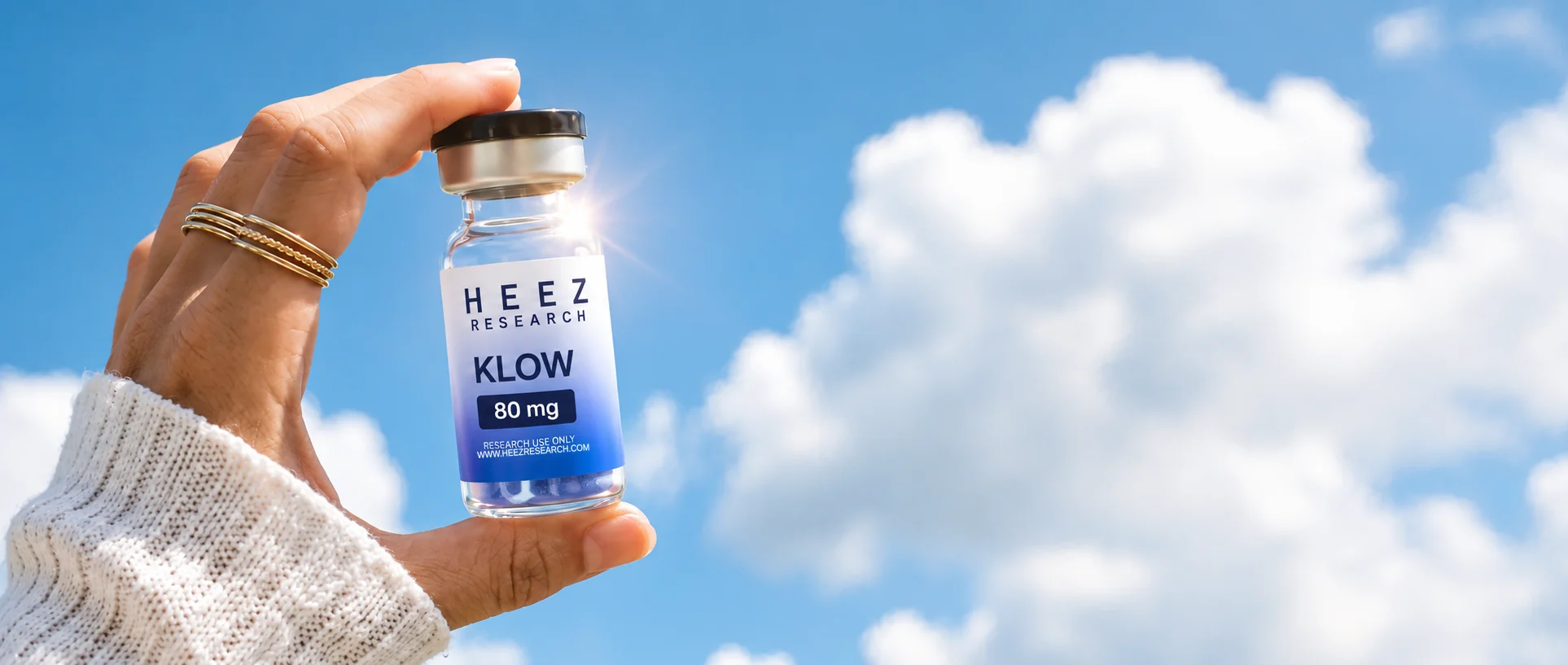 HEEZ Research KLOW 80 mg research peptide vial held against a blue sky